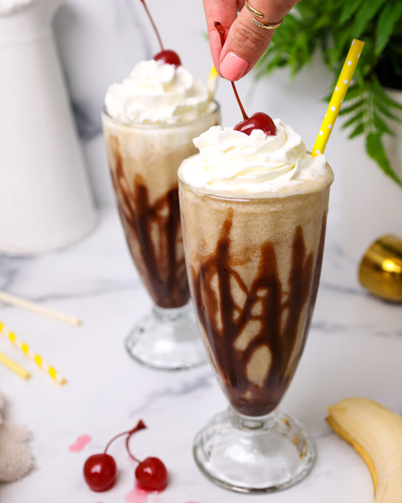 image of a cherry being added on top of a dirty monkey cocktail