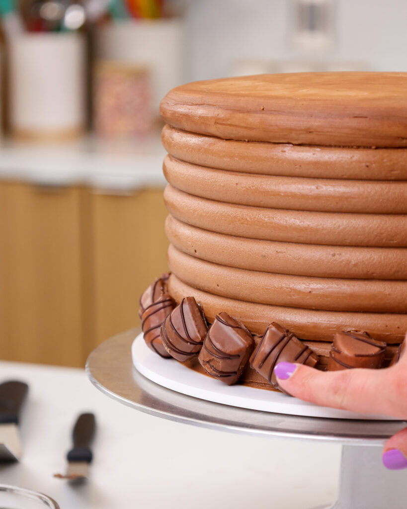 image of mini kinder bueno bars being pressed around the base of a kinder bueno cake