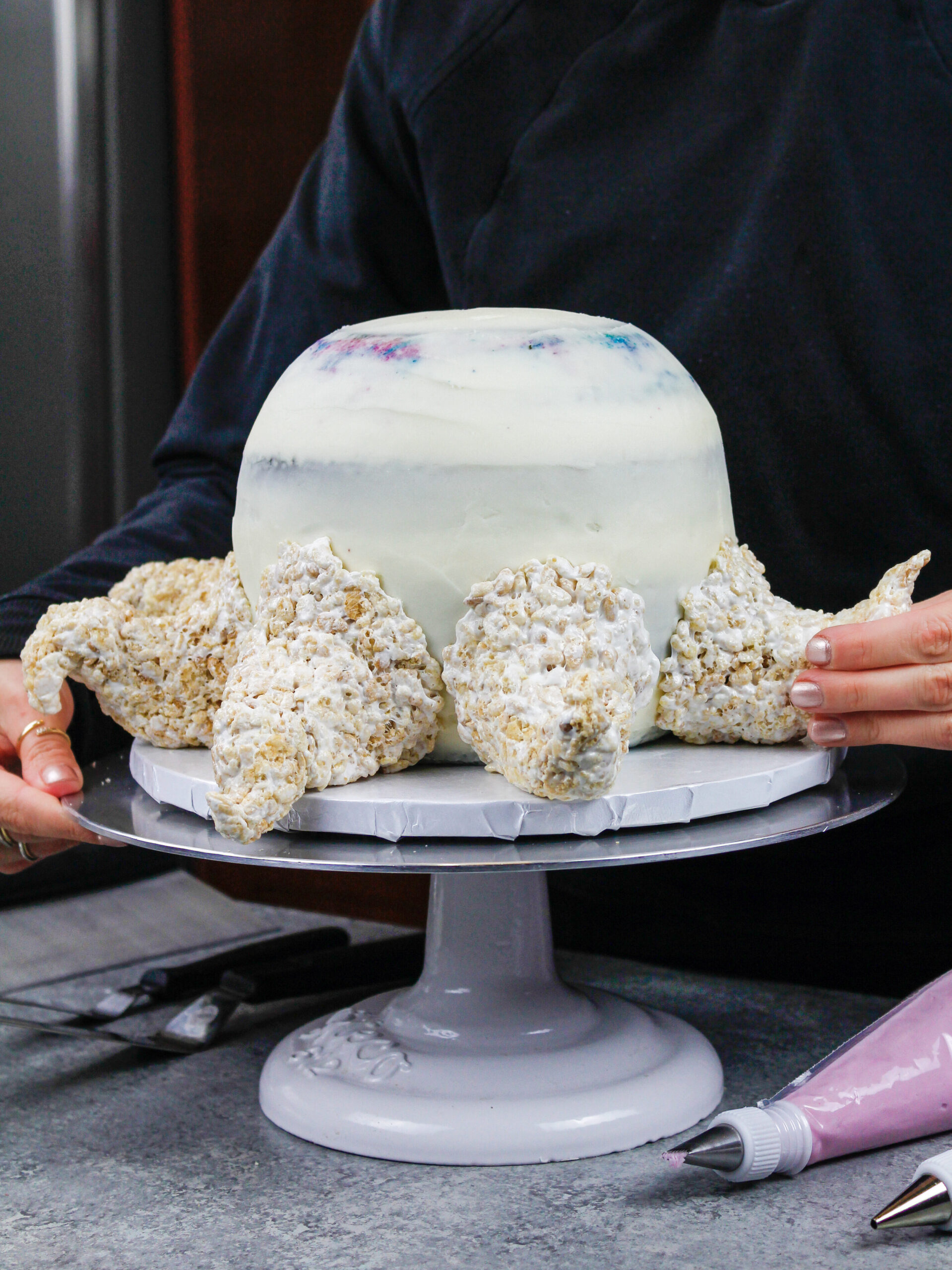 image of an octopus cake made being made with colorful cake layers, buttercream and cake decorating rice krispie