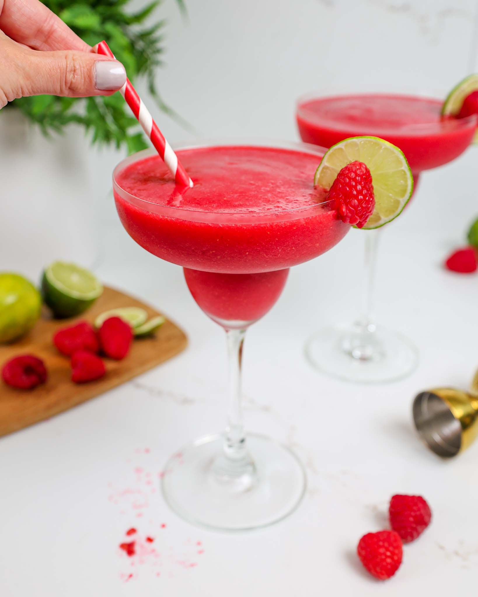 image of a lime slice being added to garnish a frozen raspberry daiquiri