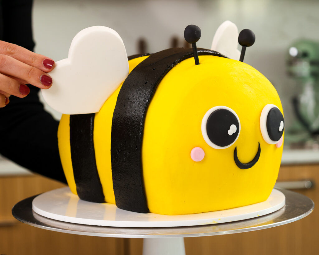 image of a fondant wing being pressed into a bumblebee cake