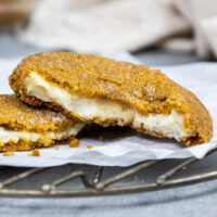 image of a pumpkin cheesecake cookie that's been broken open to show its cheesecake filling