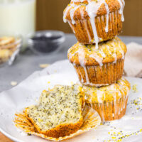 image of almond poppy seed muffins stacked with a muffin cut into to show how tender and soft it is