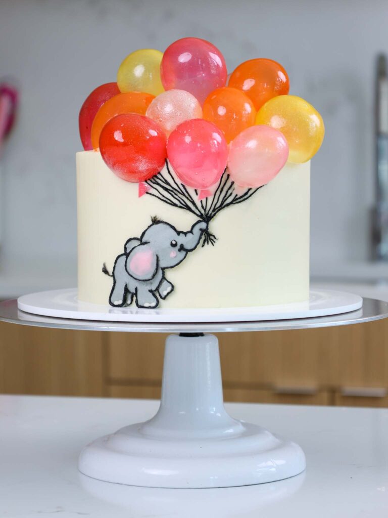 image of a cute baby shower cake that's been decorated with a baby elephant and gelatin balloons