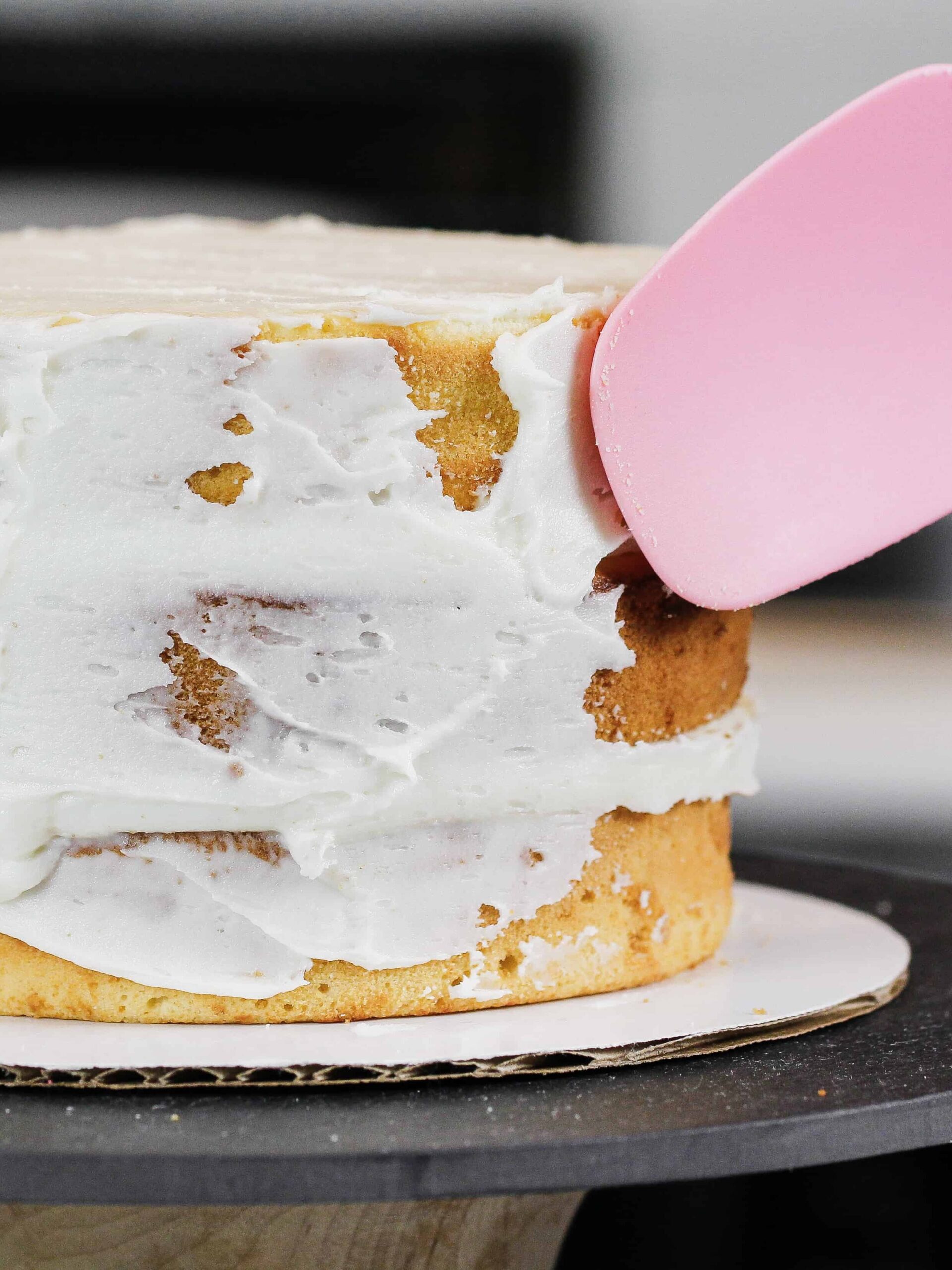 Image of a cake being frosted poorly with a rubber spatula