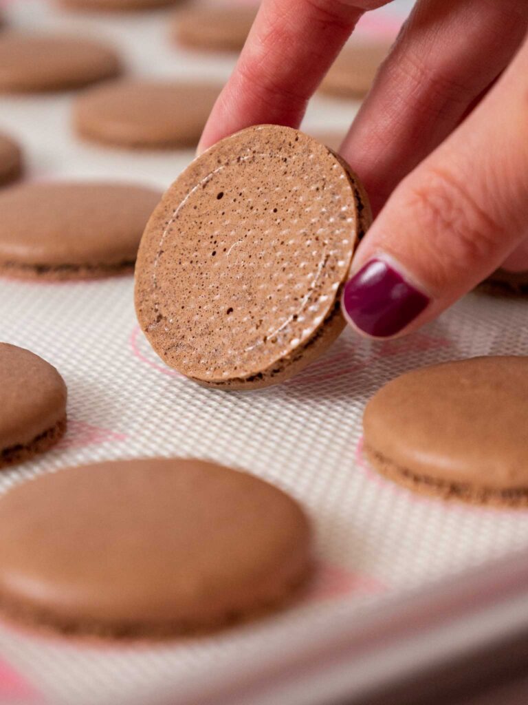 image of dark chocolate macaron shells that have been baked properly and have a shiny, smooth bottom