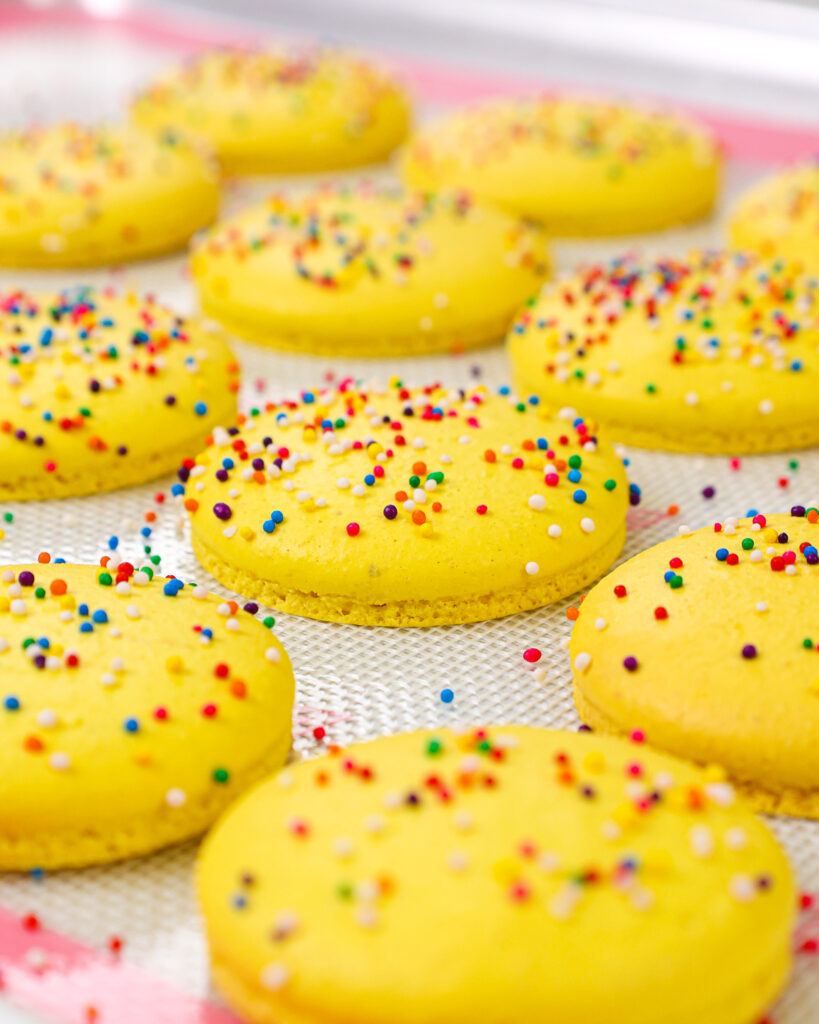 image of funfetti macaron shells that have been baked and have perfect feet