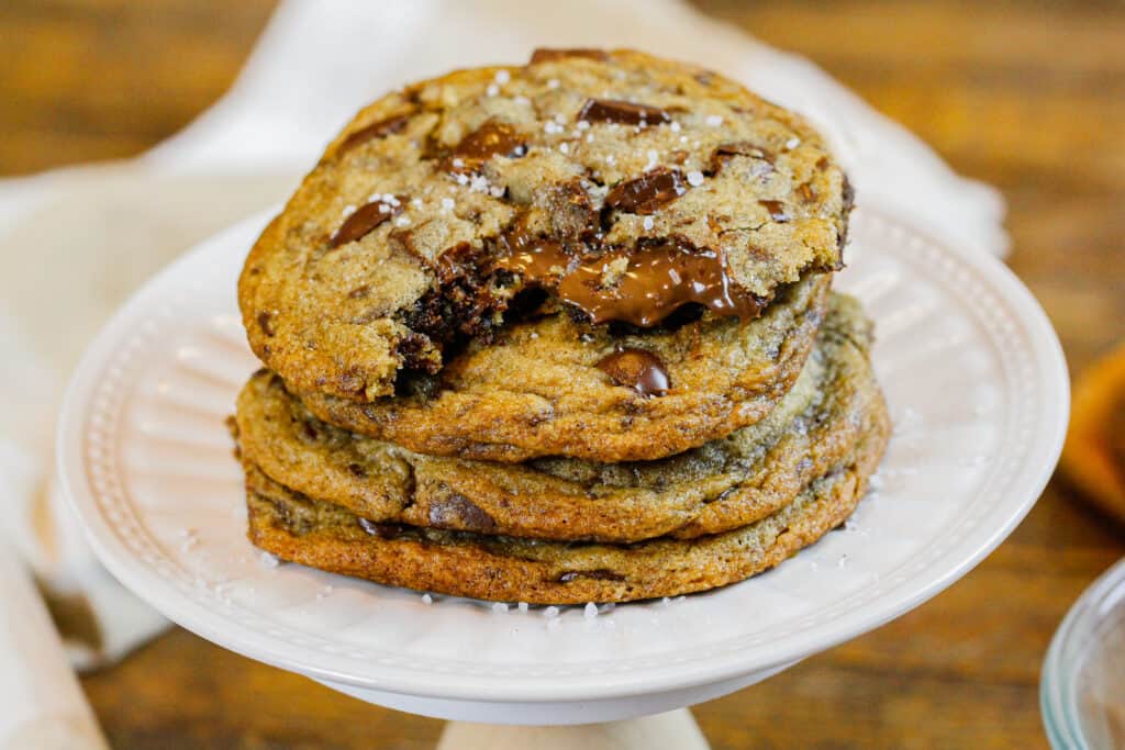 image of brown butter Nutella chocolate chip cookies in a stack with the top cookie bitten into showing the warm, melting nutella