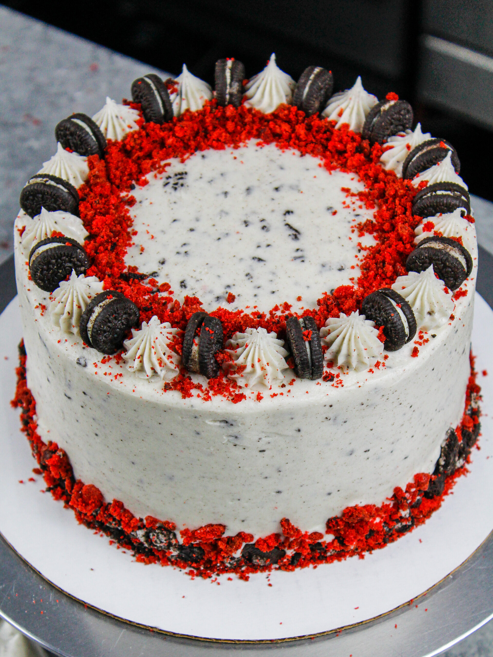 image of a red velvet oreo cake decorated with crushed oreos and red velvet cake crumbs