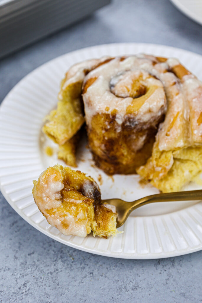 image of a pumpkin pie cinnamon roll that's been cut into to show how soft and tender it is