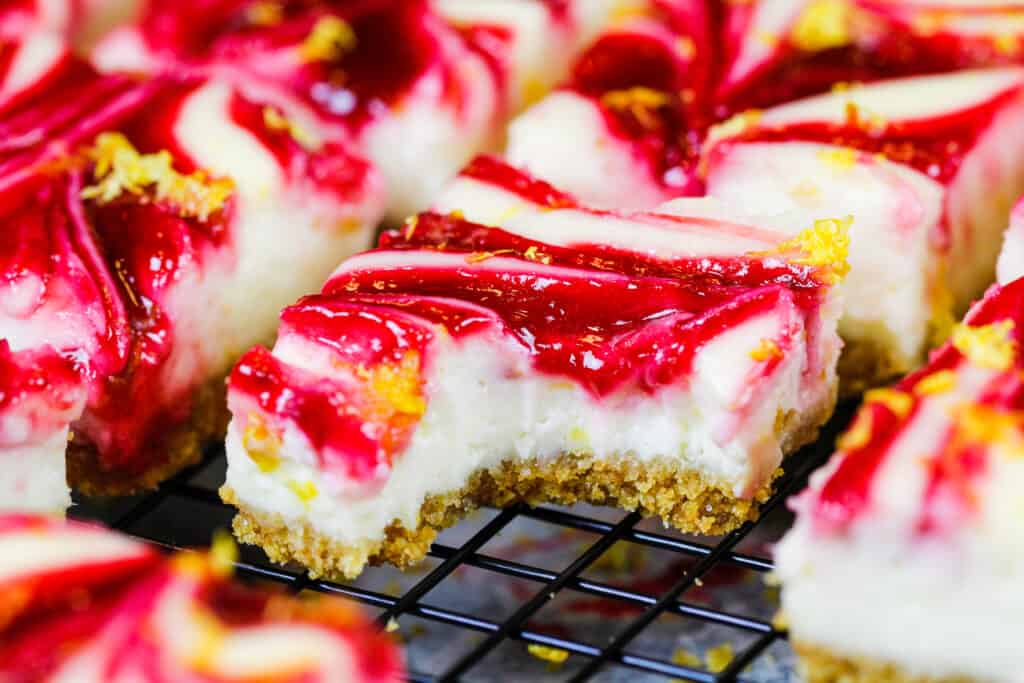 image of lemon cheesecake bars on a wire rack that have been bitten into