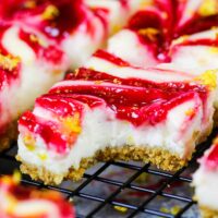 image of lemon cheesecake bars on a wire rack that have been bitten into