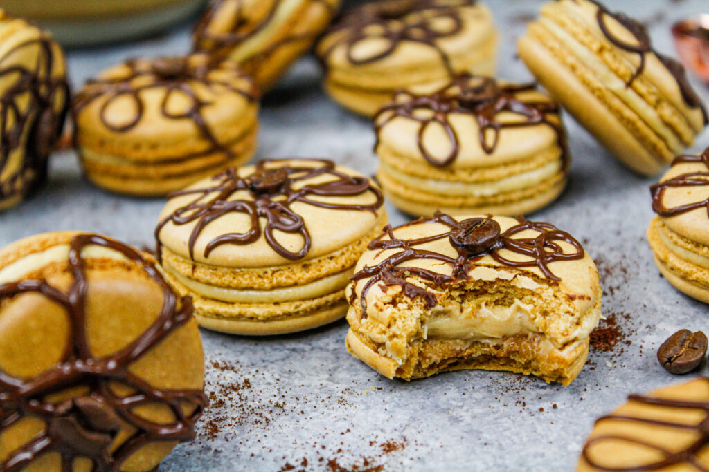 image of coffee macarons filled with coffee buttercream that have bitten into to show their full, perfect shells that was shared as part of a macaron round up