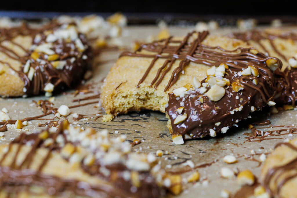 image of peanut butter cookies dipped in chocolate that have been bitten into to show how soft and chewy they are