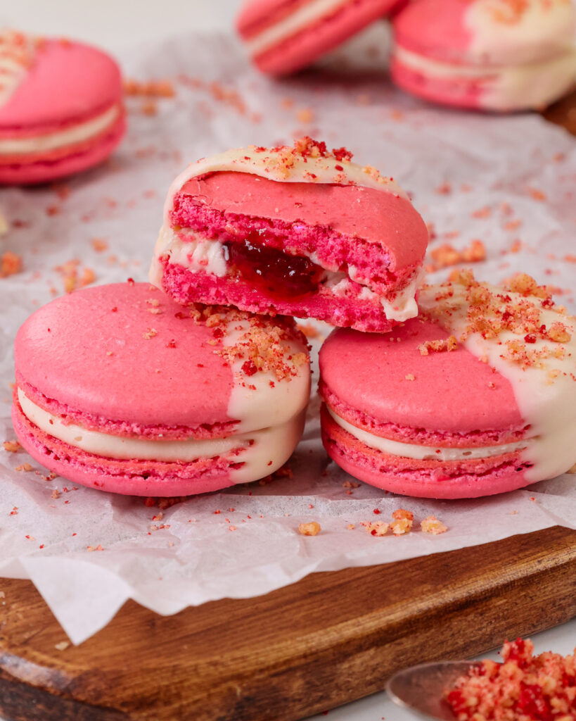 image of a strawberry shortcake macaron that's been cut in half to show its mascarpone filling and strawberry jam center