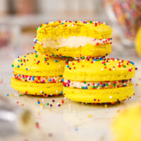 image of funfetti macarons being stacked on a plate that have been decorated with colorful nonpareil sprinkles