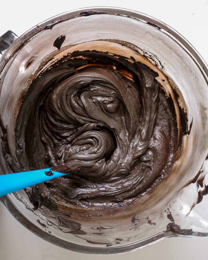 image of black dark chocolate frosting that's been mixed in a large glass bowl