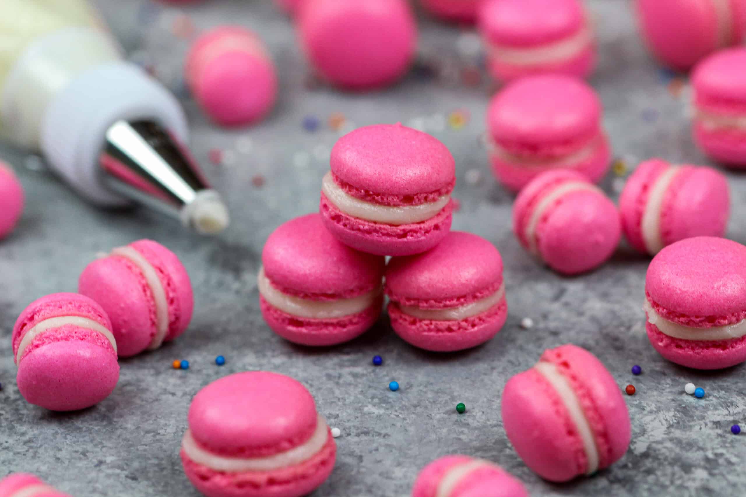 image of mini macarons colored pink with gel food coloring and filled with american buttercream