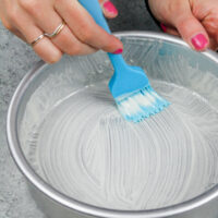 image of homemade cake release being brushed into a cake pan before batter is poured in to prevent the cake layers from sticking