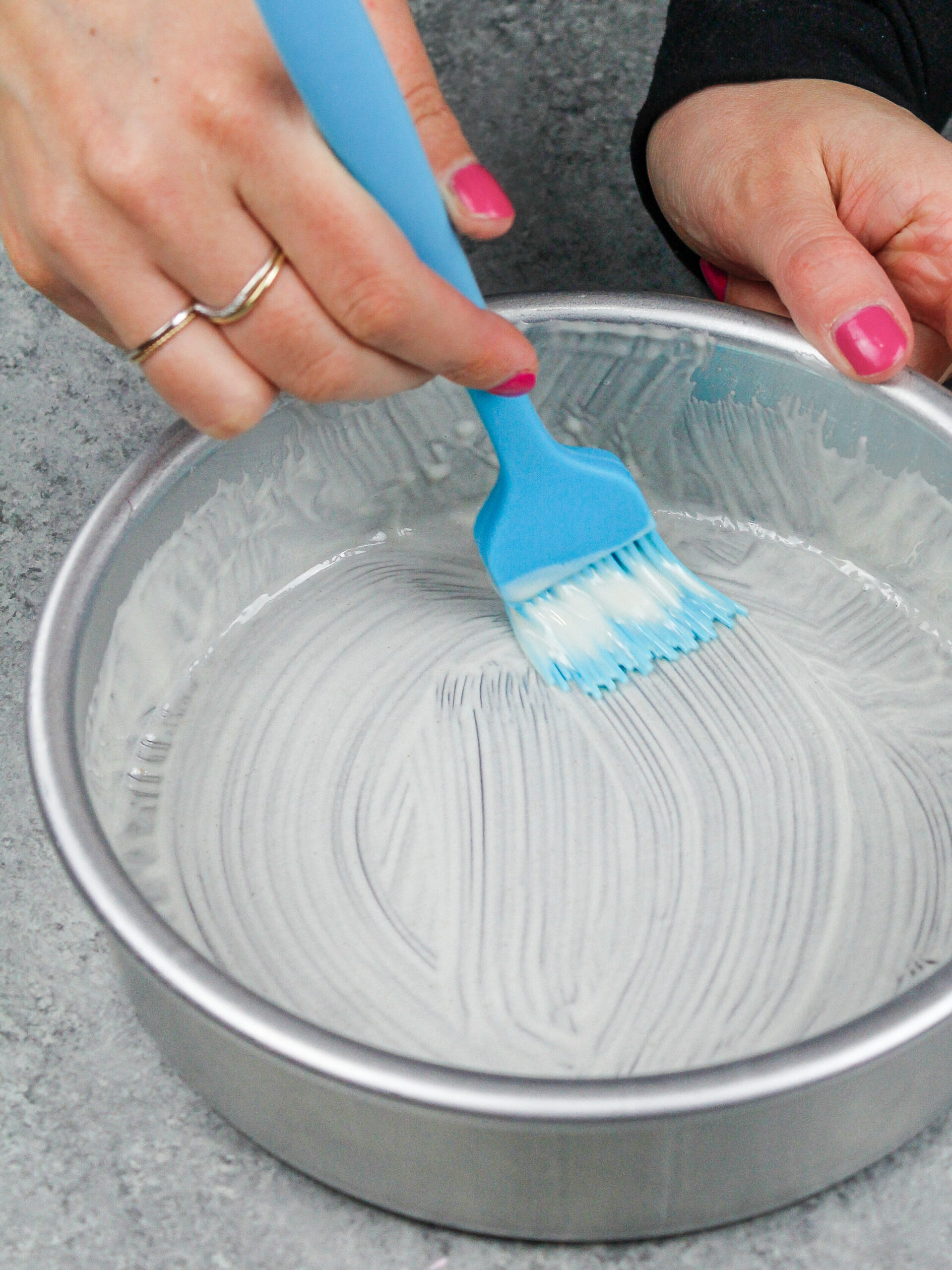 image of homemade cake release being brushed into a cake pan before batter is poured in to prevent the cake layers from sticking