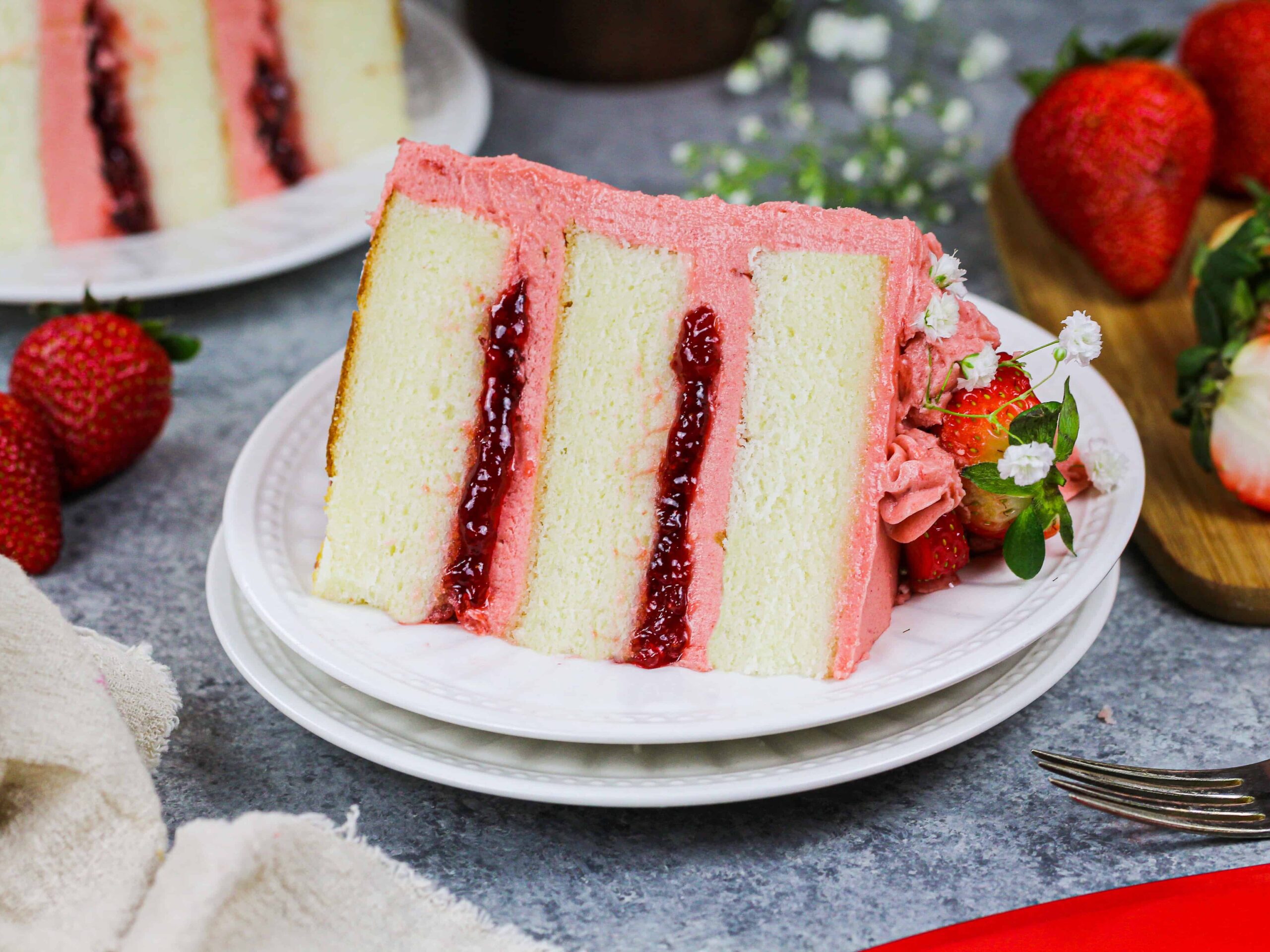 image of a slice of vanilla strawberry cake filled with strawberry jam and strawberry frosting