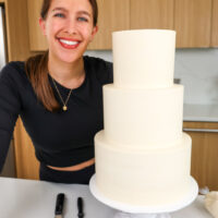 image of chelsey white next to a wedding cake made with the perfect hybrid frosting that she likes to call her not too sweet buttercream