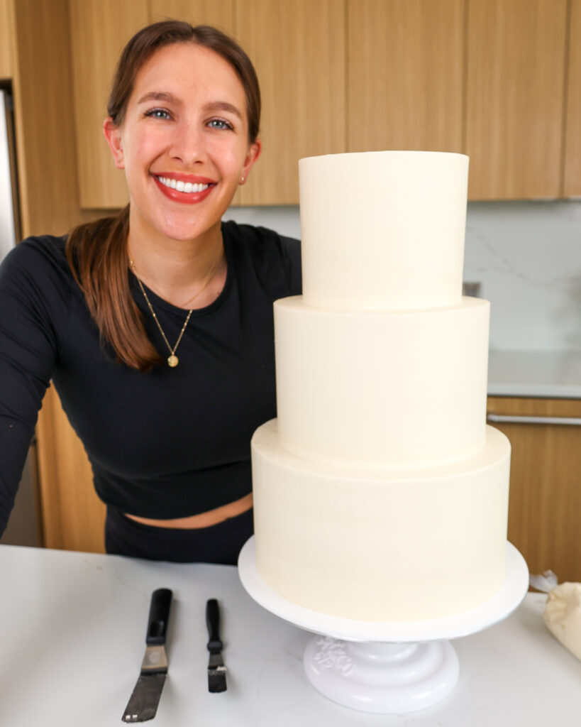 image of chelsey white next to a wedding cake made with the perfect hybrid frosting that she likes to call her not too sweet buttercream