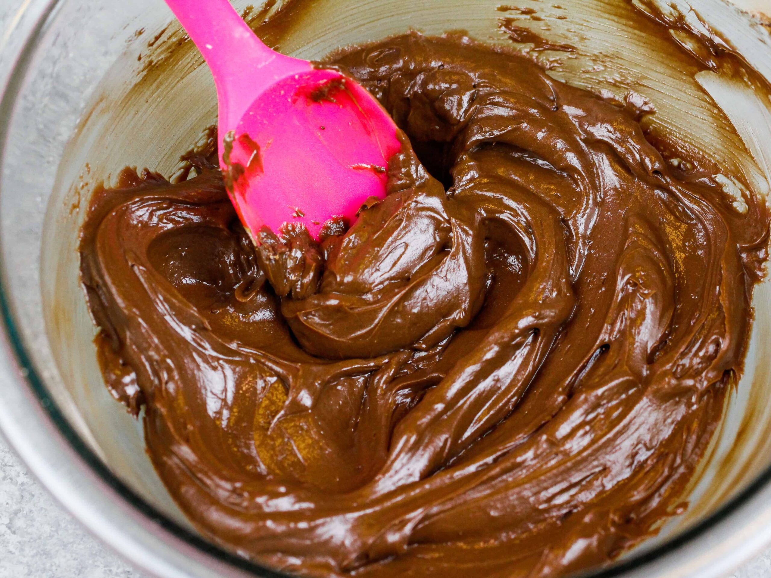 image of a small batch of dark chocolate buttercream frosting that's been made to frost mini chocolate cupcakes 