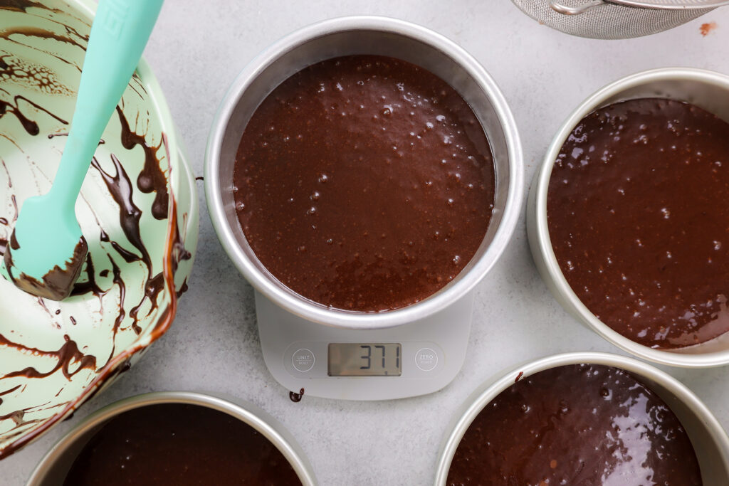 image of cake pans being weighed to make sure they have the same amount of batter in each pan to help them bake up to the same height