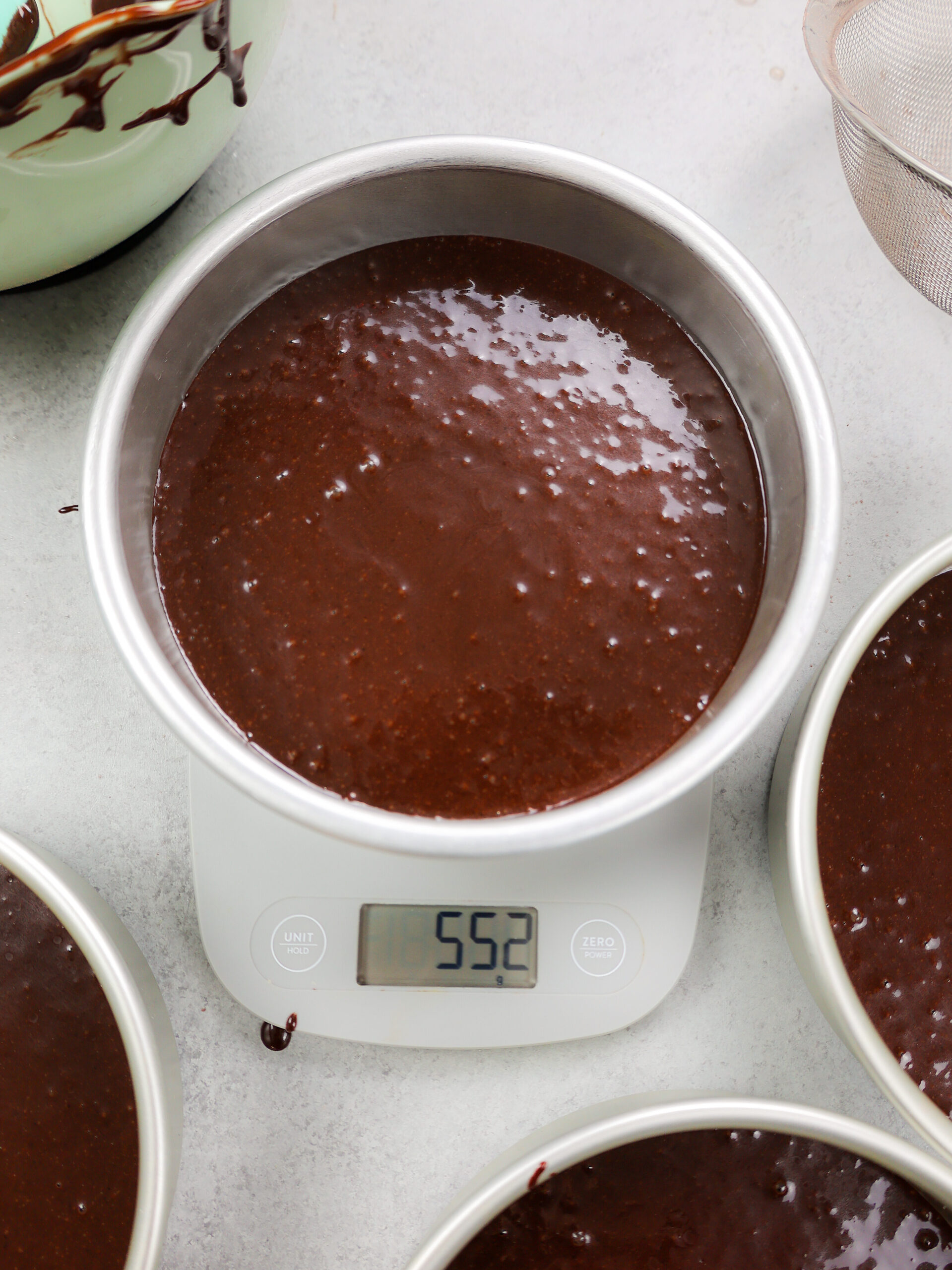 image of chocolate cake batter being weighed on a scale to make sure all the pans have the same amount of batter