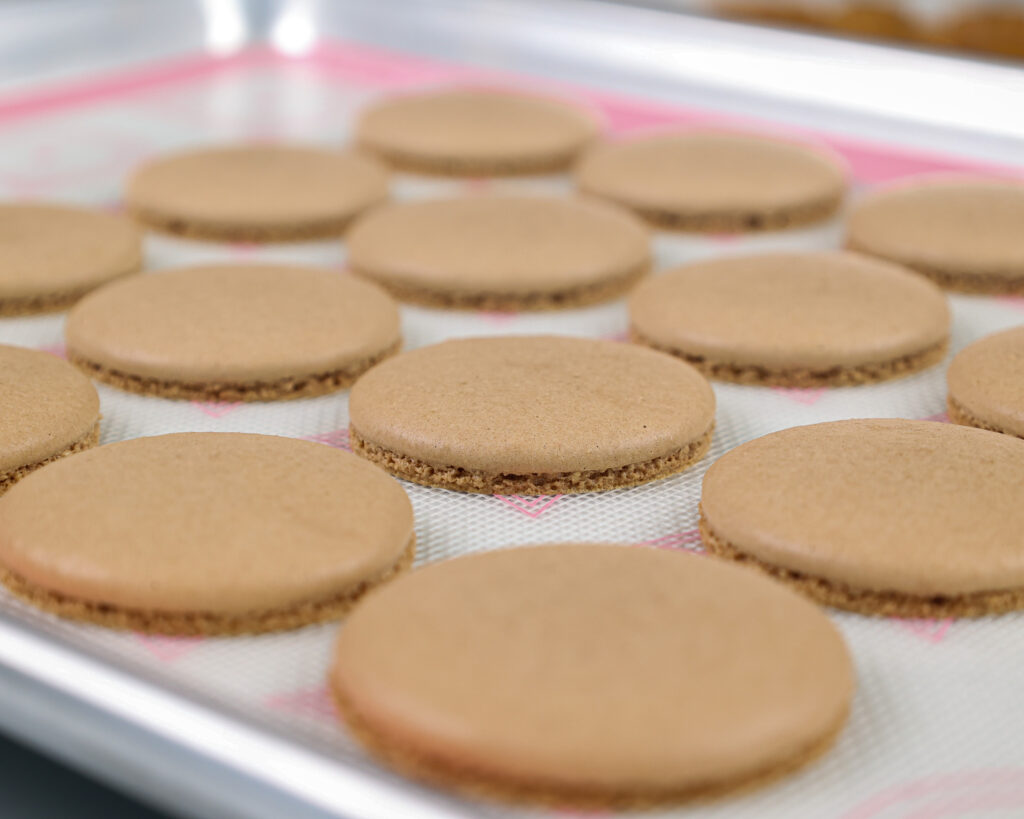 image of baked chocolate macaron shells that are cooling on a silpat mat