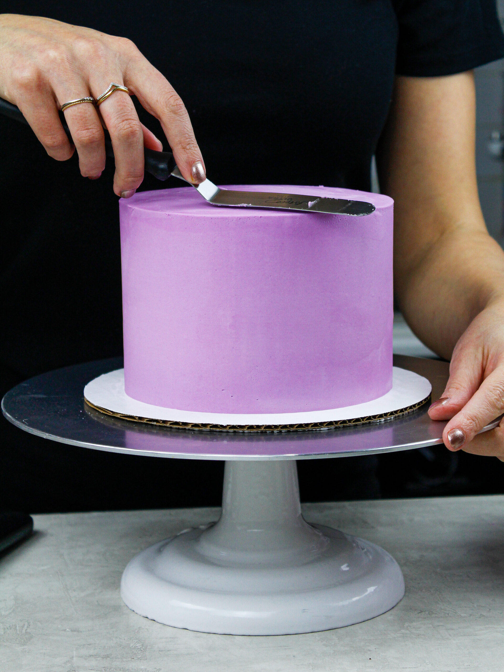 image of a buttercream cake being frosted with sharp edges and smooth sides to show How to Frost a Cake Smoothly