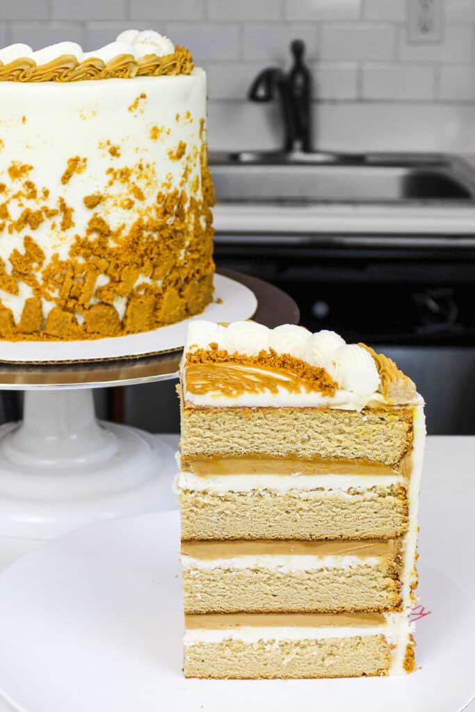 image of cookie butter cake slice on a plate showing it's cookie butter frosting and filling