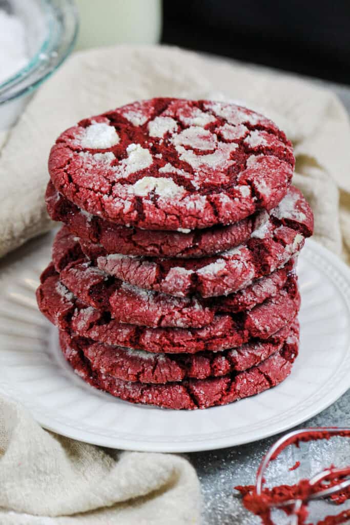 image of red velvet crinkle cookies that have been stacked on a small plate and are ready to be eaten