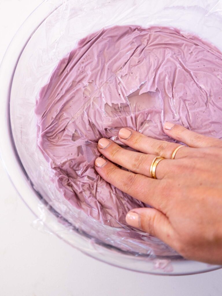 image of blackberry mousse being covered with plastic wrap before being place din the fridge to set