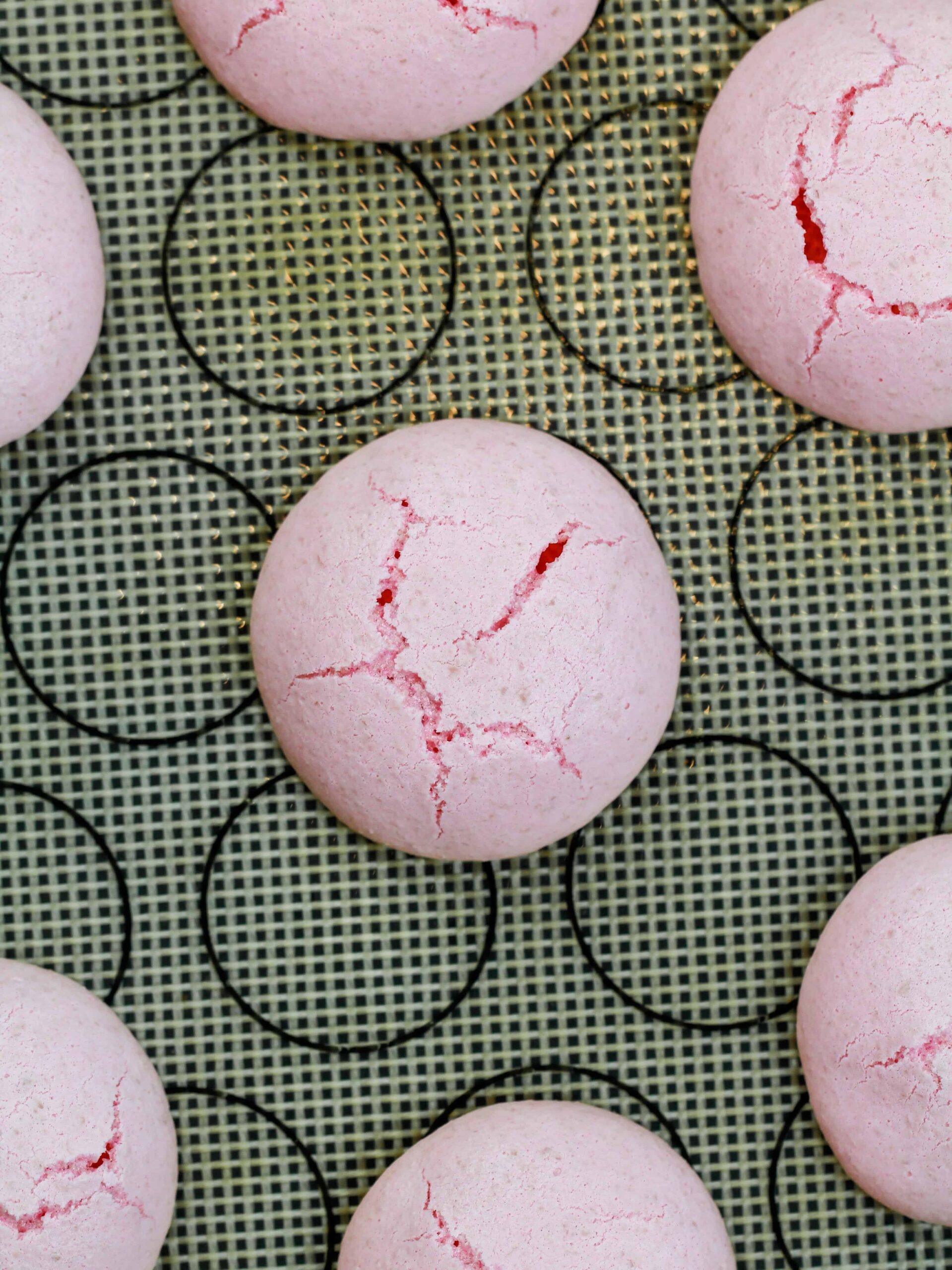 image of cracked italian macarons that were baked in too hot of an oven included in a macaron troubleshooting guide explaining how to avoid this issue