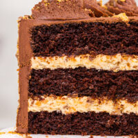 image of a butterfinger cake that's been cut into to show its crunchy peanut butter butterfinger filling and tender chocolate cake layers