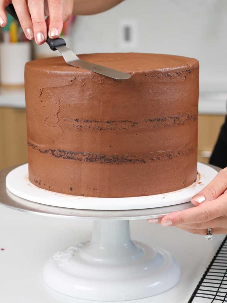 image of a chocolate cake being crumb coated with chocolate buttercream