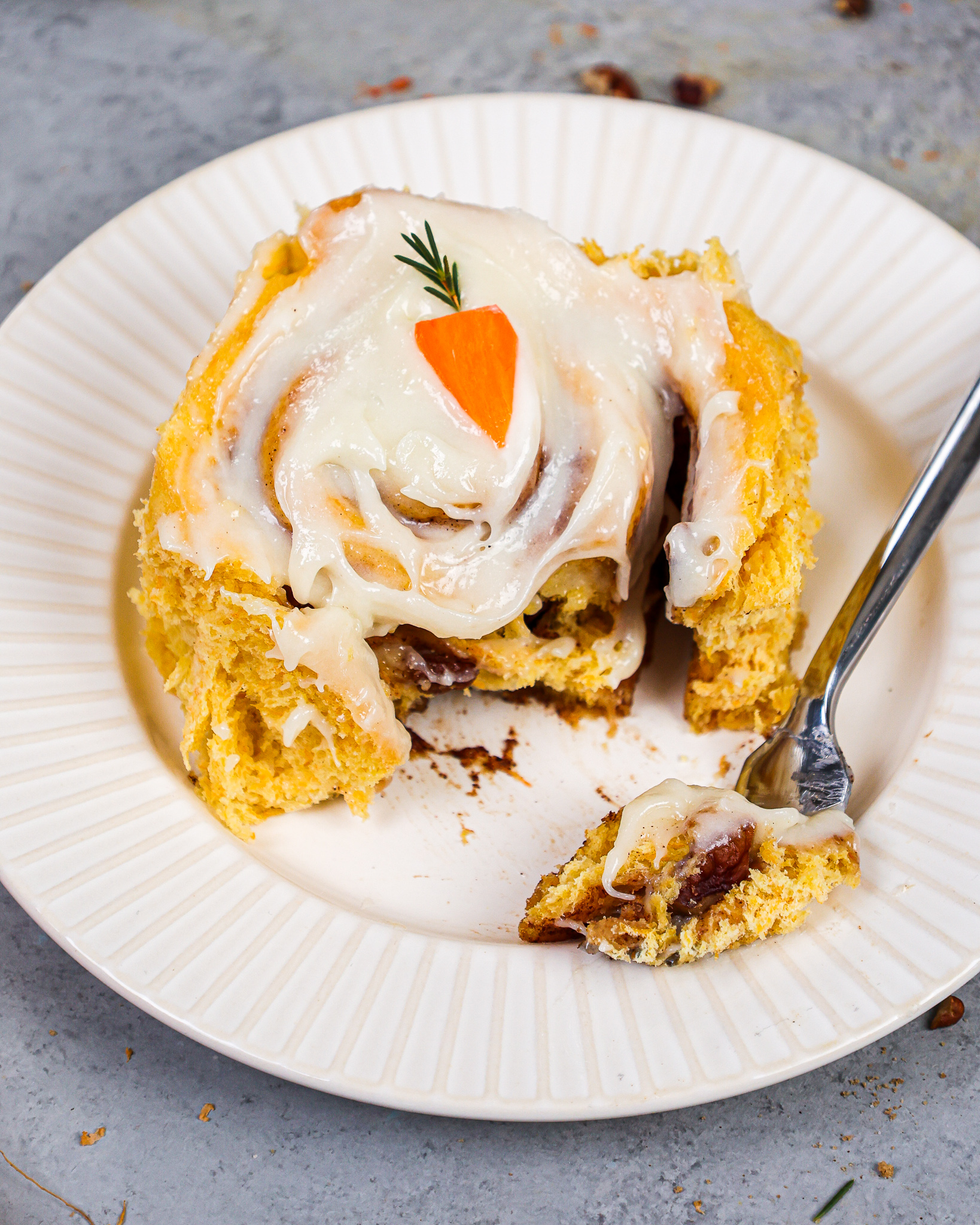 image of a fluffy carrot cake cinnamon roll that's been cut into to show how tender and soft it is