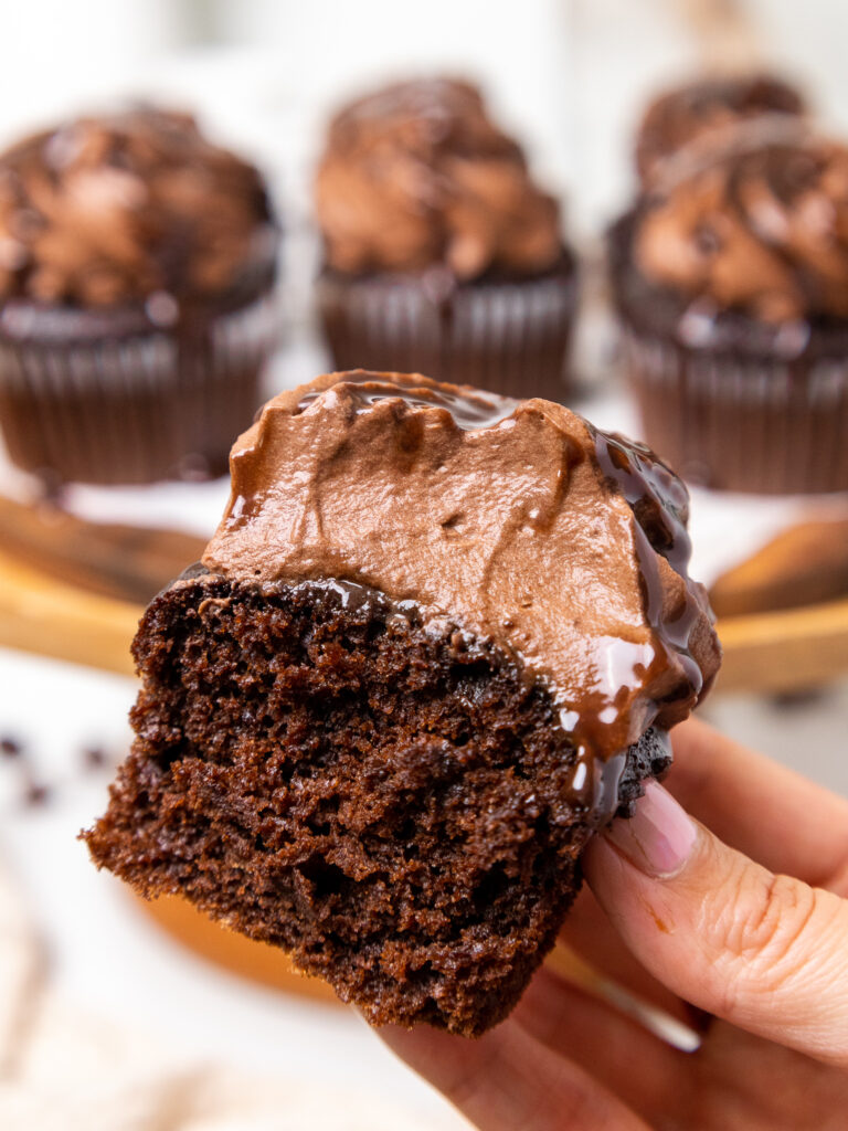 image of a cupcake that's been frosted with chocolate whipped cream and has been bitten into to show how fluffy and light the frosting is