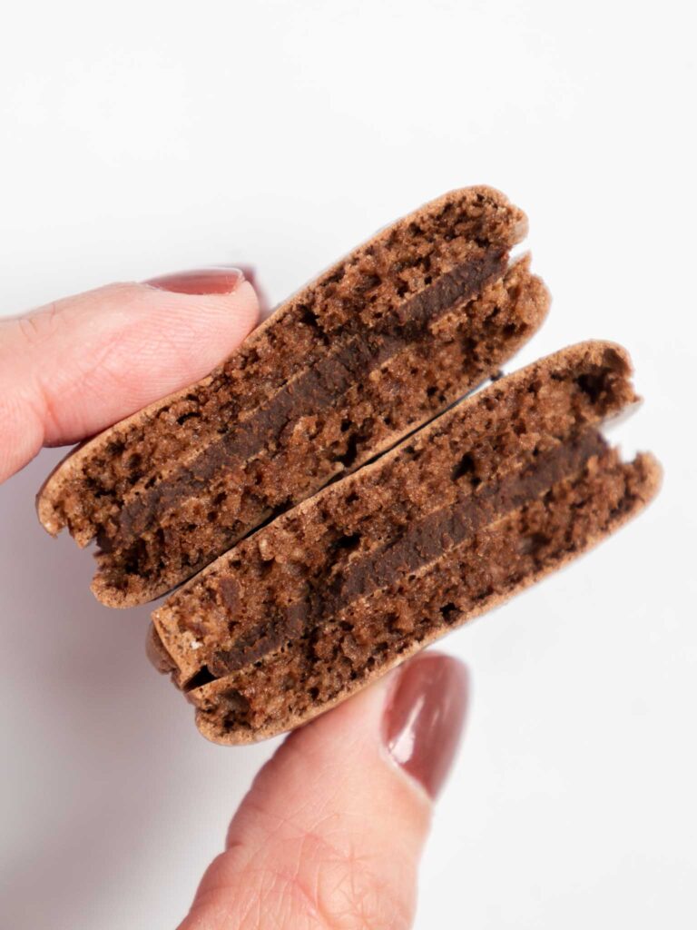 image of dark chocolate macarons that have been cut in half to show that the shells are full