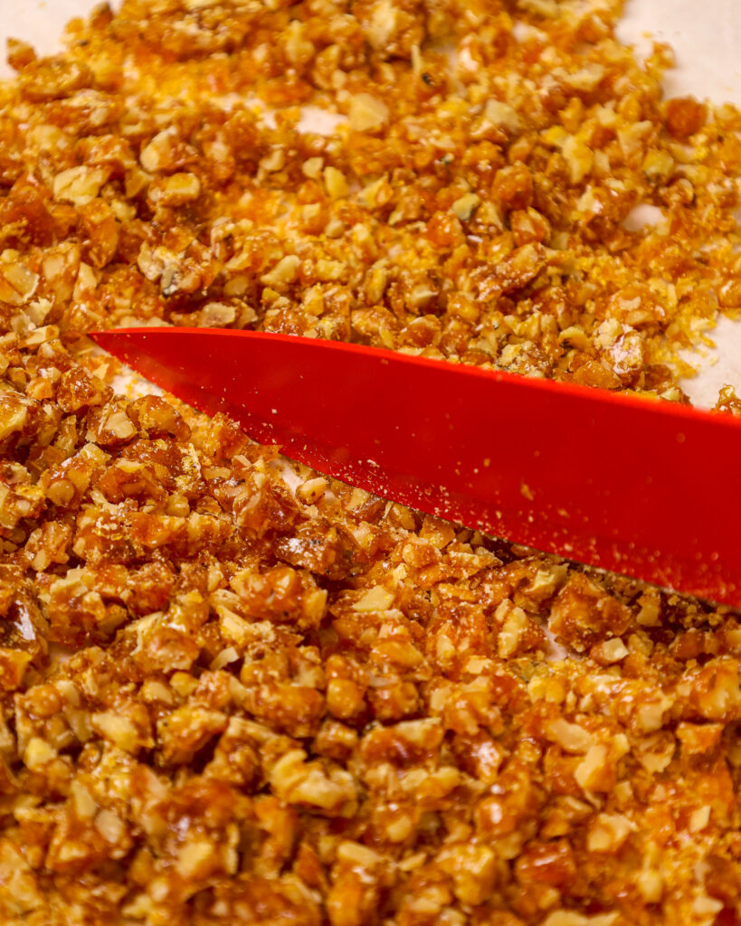 image of walnut brittle being cut into small pieces with a share knife