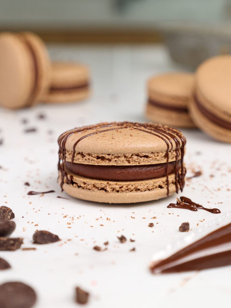 image of a french chocolate macaron being filled with a semi sweet chocolate ganache