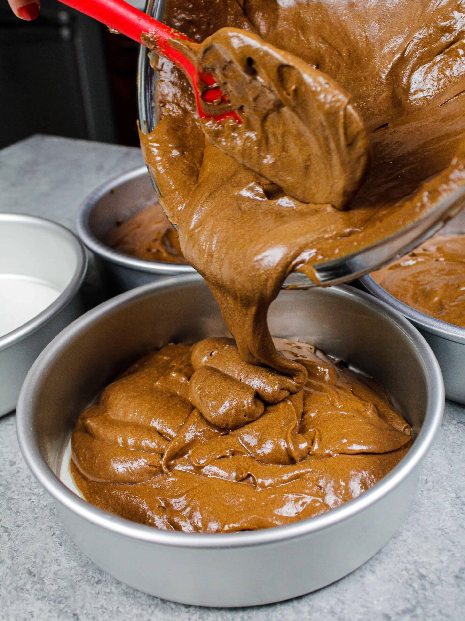 image of chocolate mocha cake batter being poured into cake pans