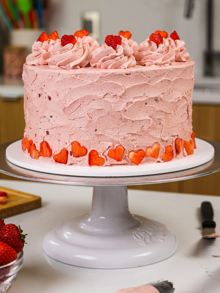 image of a vanilla cake that's been frosted with a strawberry swiss meringue buttercream frosting