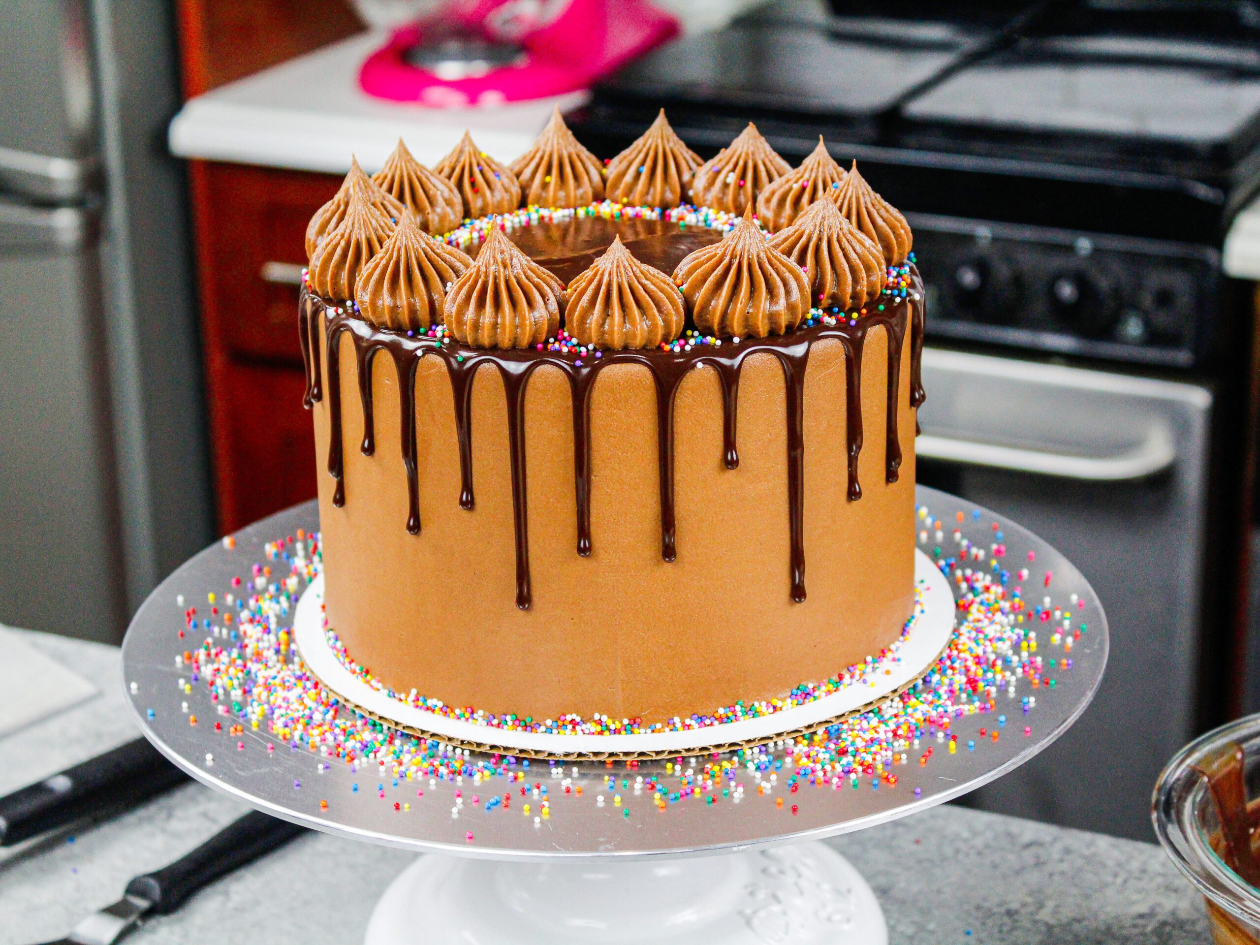 image a gorgeous chocolate drip cake decorated with small rainbow nonpareil sprinkles