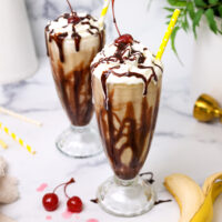 image of a dirty monkey drink that's been made with rum and bananas and has been poured into a chocolate syrup lined milkshake glass