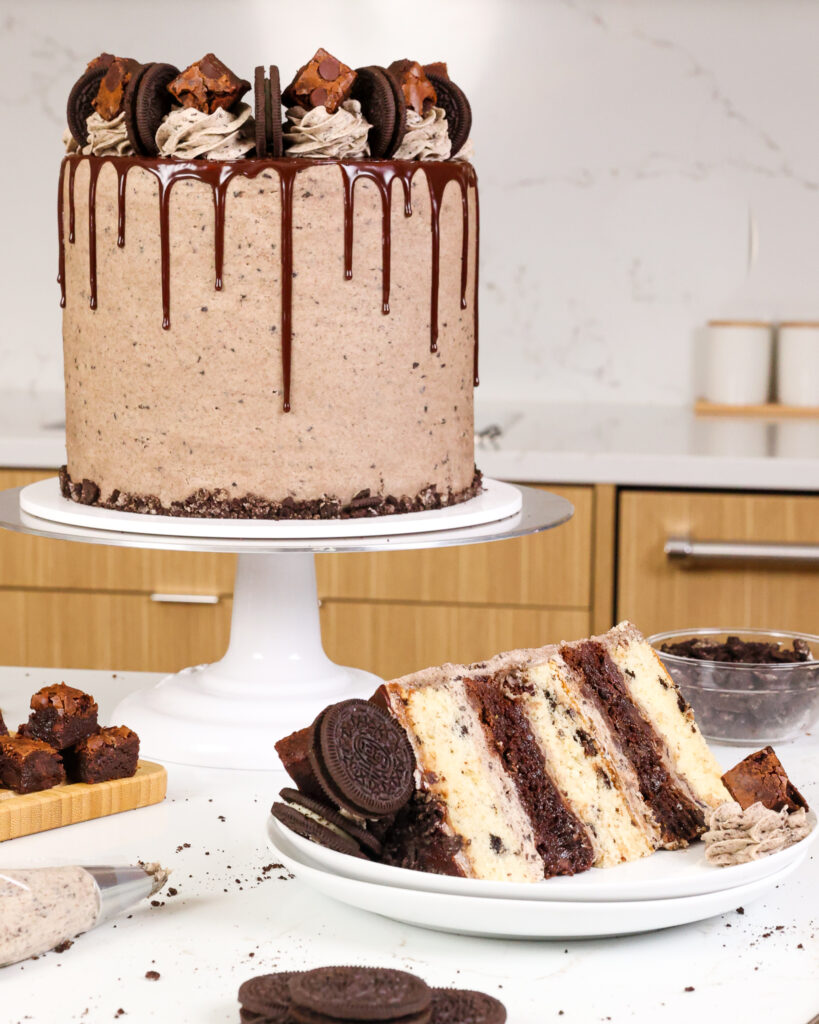 image of a brownie oreo cake that's been frosted with oreo buttercream and cut into to show it's alternating layers or oreo cake and brownie