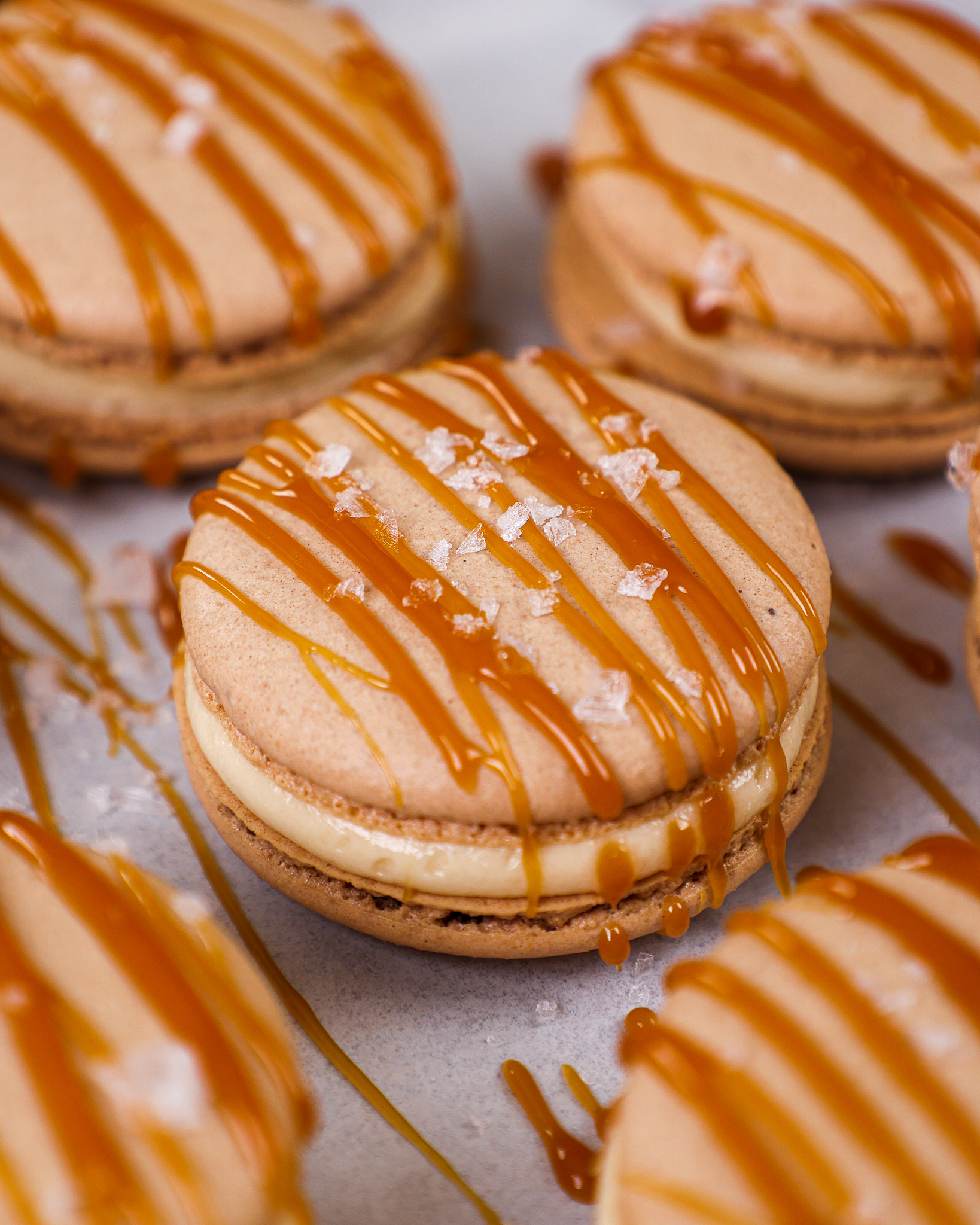 image of a salted caramel macaron decorated with a drizzle of caramel and a sprinkle of flakey sea salt