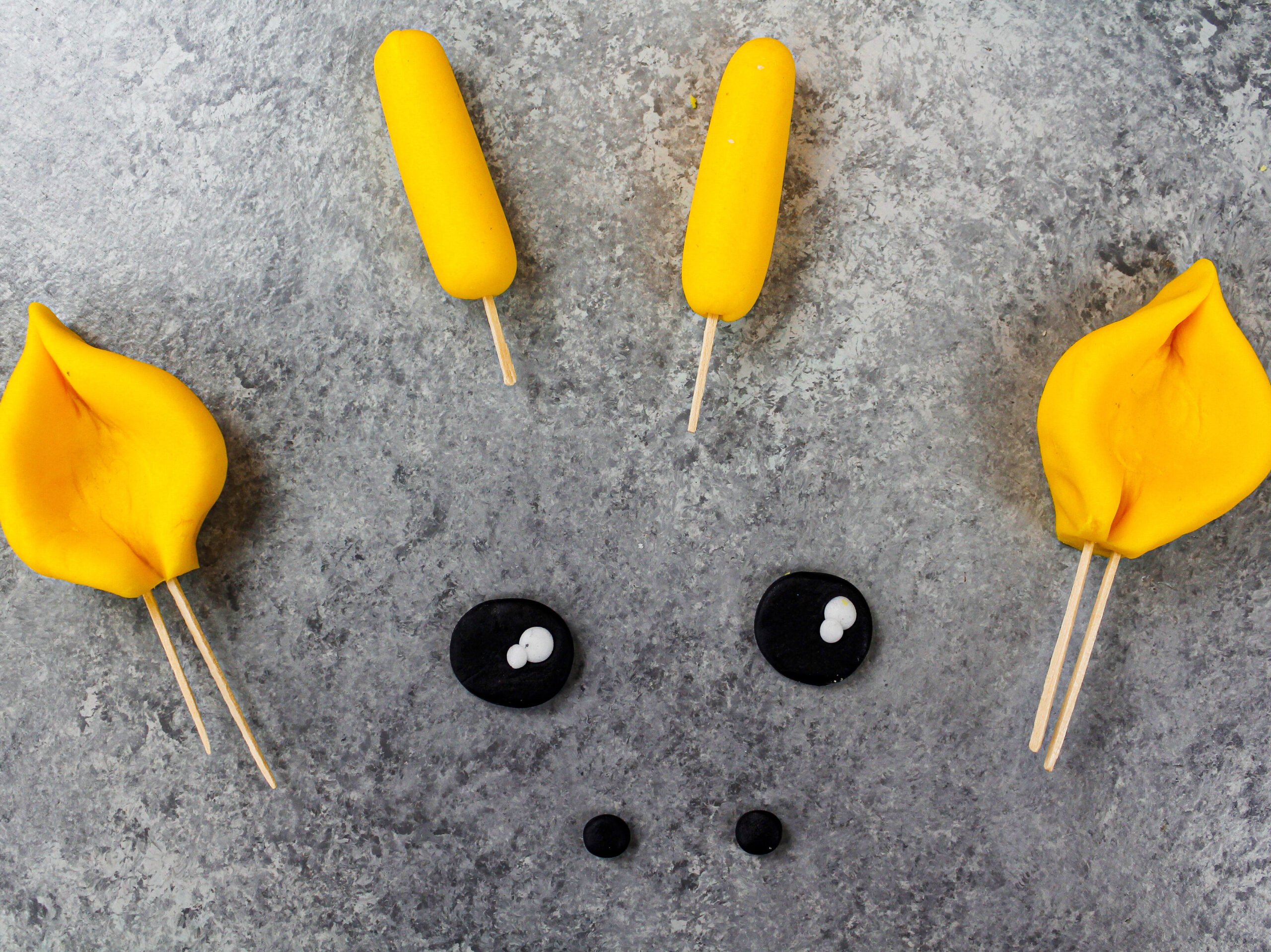 image of yellow and black fondant used to make the eyes and ears for a giraffe cake